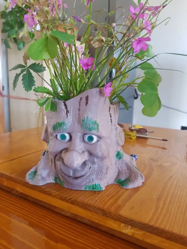 vaso portafiori a forma di base di tronco d'albero con occhi, naso e bocca. Realizzato instampa 3d e dipinto a mano, vista principale.