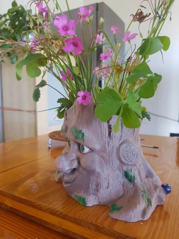 vaso portafiori a forma di base di tronco d'albero con occhi, naso e bocca. Realizzato instampa 3d e dipinto a mano, vista laterale.