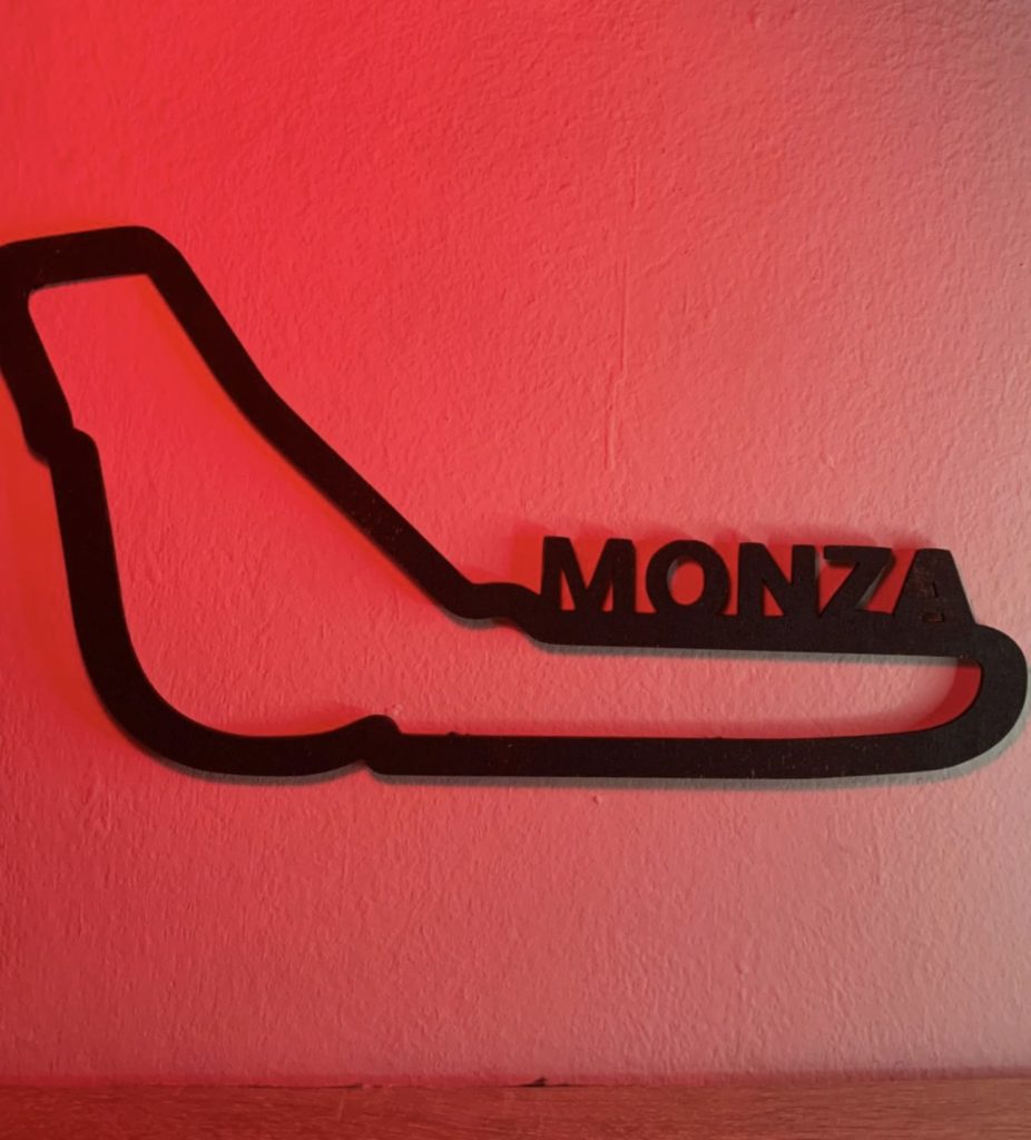 Circuito di formula 1 di Monza, in plexiglass nero tagliato a laser. fissato su muro bianco. Vista con illuminazione rossa e mensola sottostante