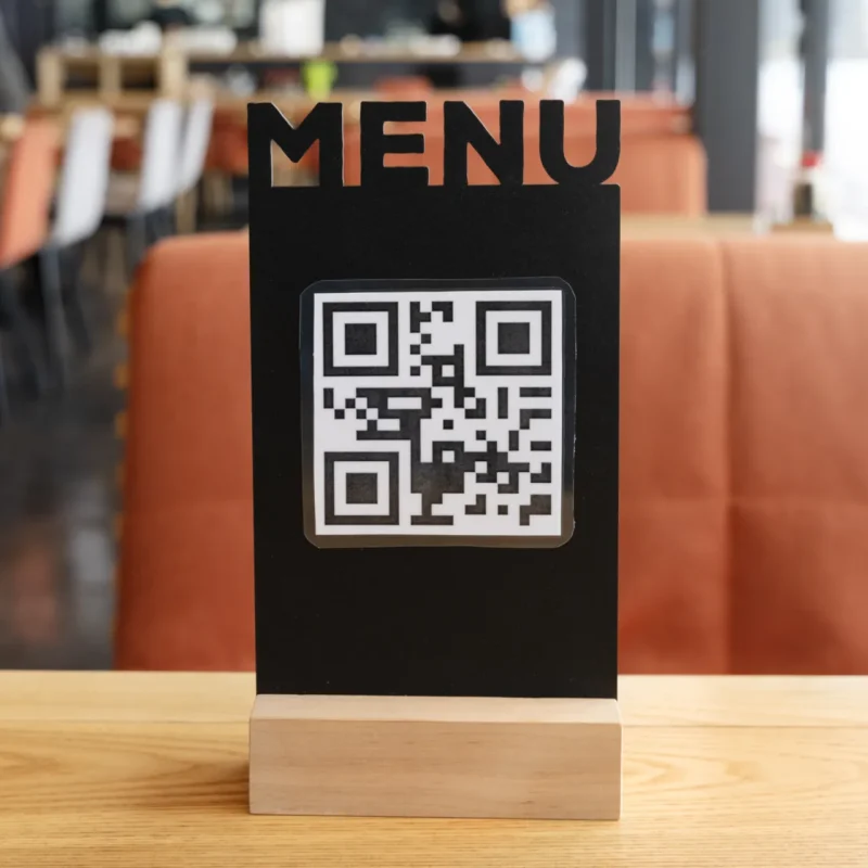 menu con QR code stampato su un supporto, appoggiato su un tavolo da ristorante